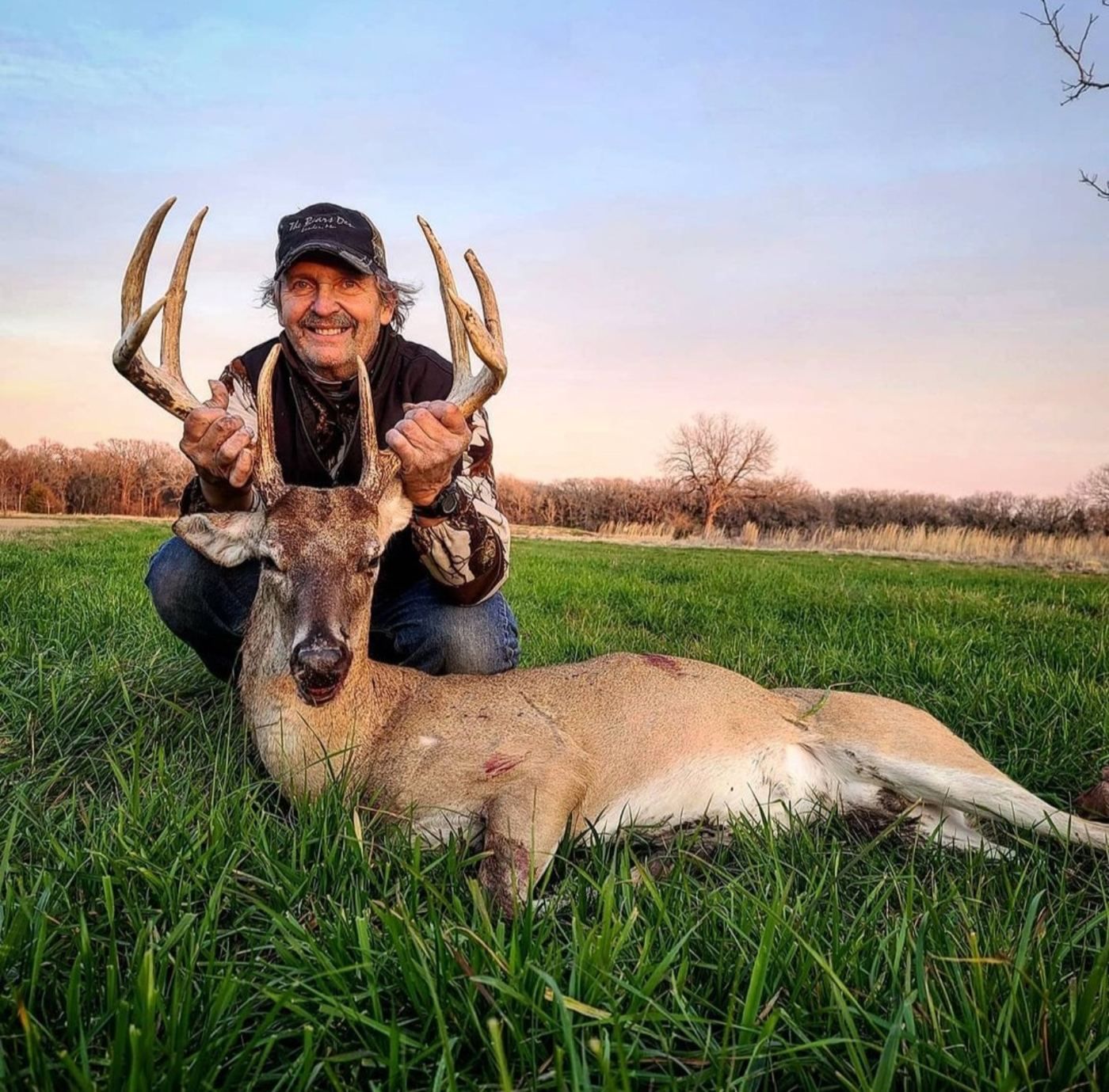 Hunter with a whitetail buck at sunset at The BigWoods